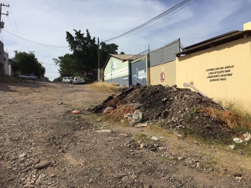 Calle Julián Adame con piedras y montón de tierra