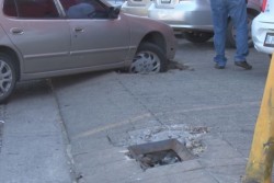 Cae automóvil en registro de drenaje sin tapa ubicado sobre banqueta de plaza comercial